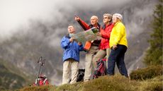 A foursome of older people consult a map while on a mountain hike.