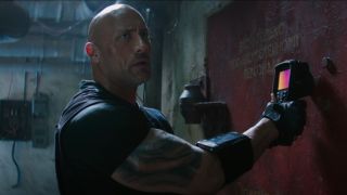 Dwayne Johnson holding a sensor up to a door in Hobbs and Shaw.