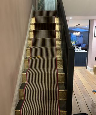 staircase with gold leaf and a striped runner
