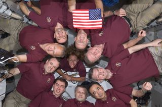 The combined crews of STS-135 and Expedition 28 pose with the STS-1 flag on the International Space Station in July 2011. The STS-135 crew included NASA astronauts Chris Ferguson, Doug Hurley, Sandy Magnus and Rex Walheim; the ISS Expedition 28 crewmembers were JAXA astronaut Satoshi Furukawa, NASA astronauts Ron Garan and Mike Fossum and cosmonauts Andrey Borisenko, Alexander Samokutyaev and Sergei Volkov.