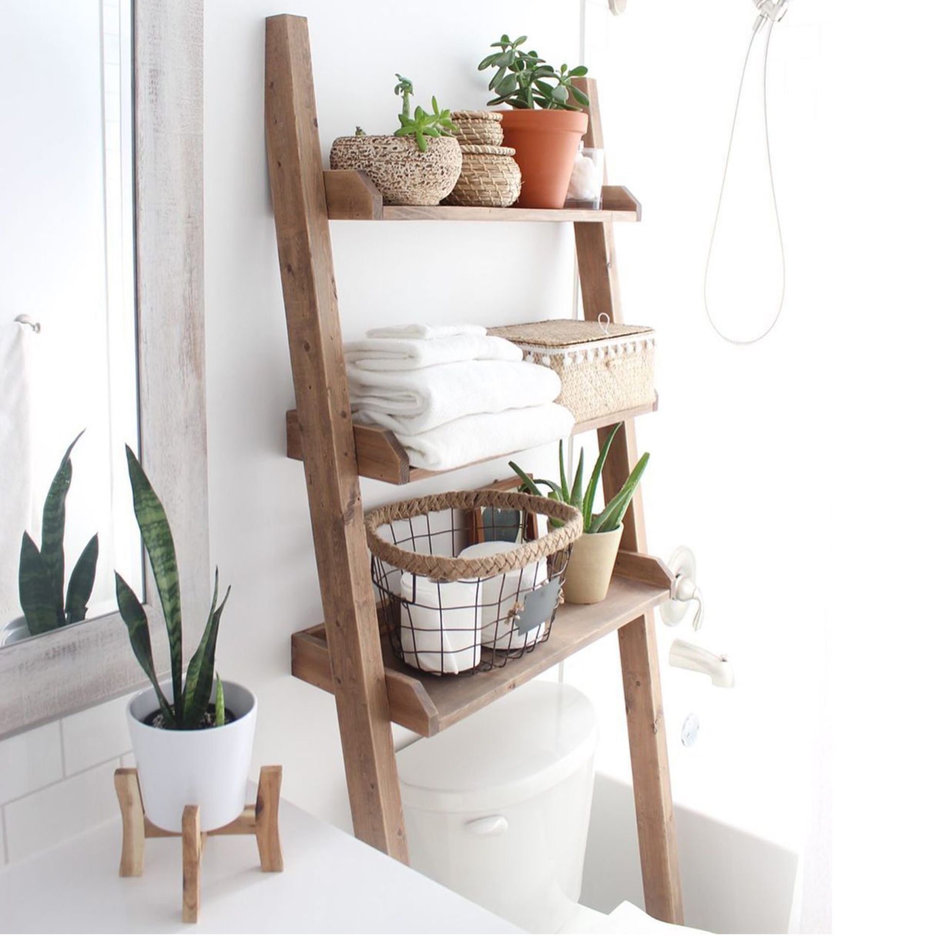 Tangga rak pedesaan di atas toilet, dirancang dengan handuk, tanaman, dan keranjang penyimpanan anyaman