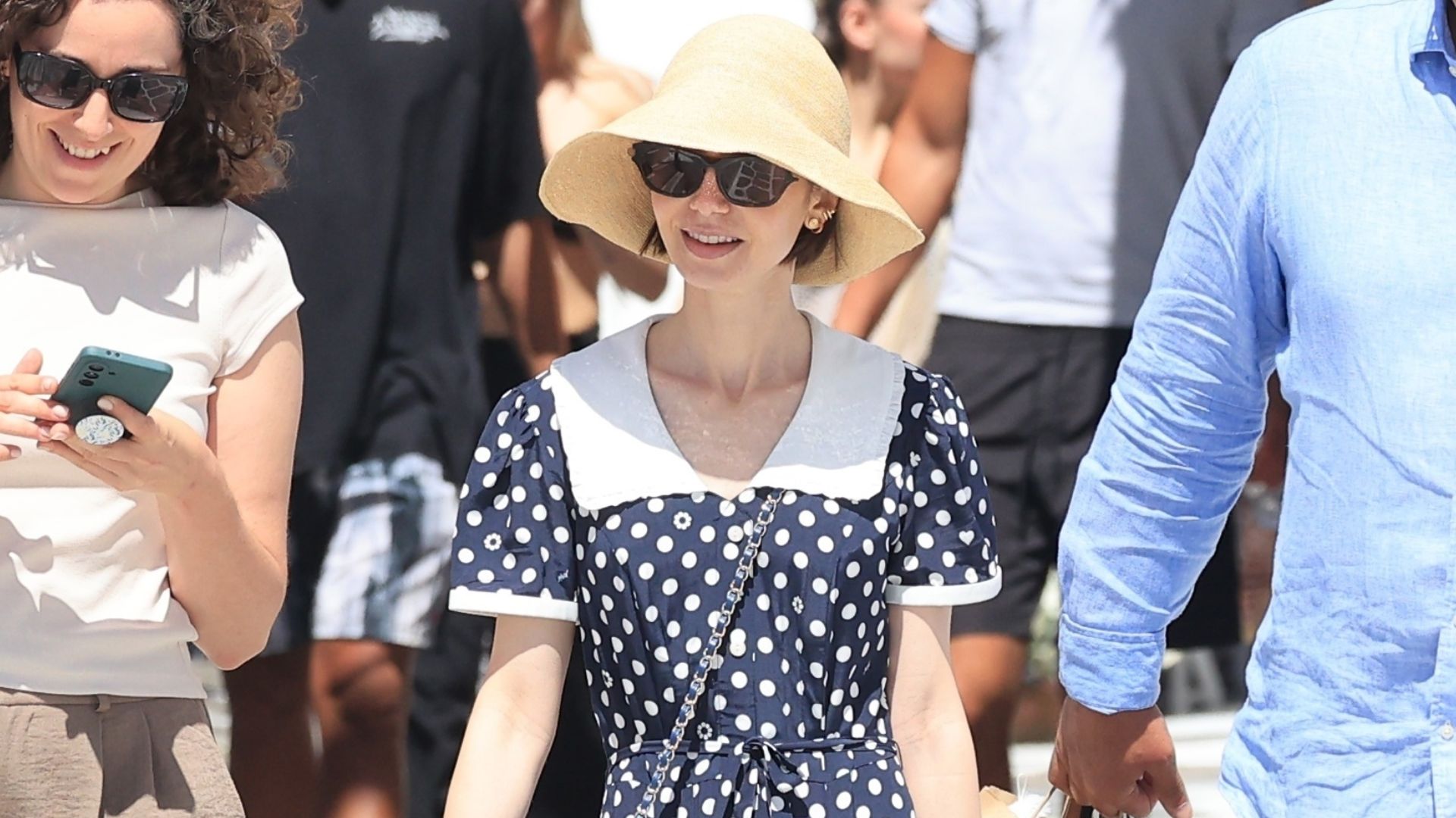 Lily Collins wears beige mesh ballet flats with a polka dot dress and a straw hat.