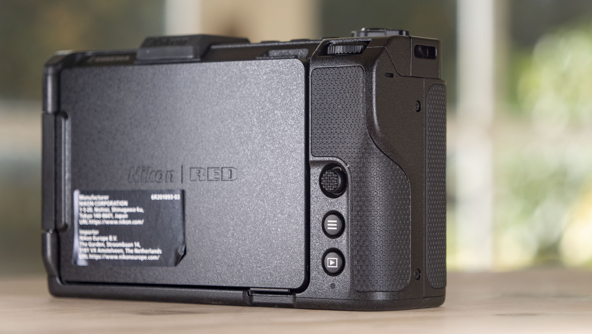 Nikon ZR product photos – camera on a wooden table, rear with screen folded away