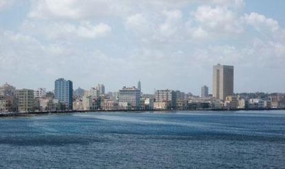 Landscape image showing the city of Havana with high-rise buildings sitting at the edge of a body of water