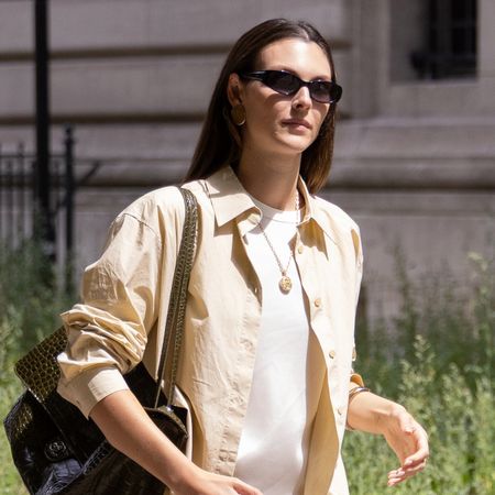 Vittoria Ceretti in Paris wearing a yellow button-down over a white T-shirt with white striped pull-on shorts and brown suede slipper mules.