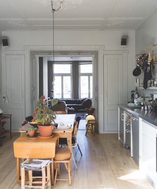 Farrow & Ball light gray kitchen with kitchen table in middle, industrial style kitchen units, wooden floor, paneling, view to living room