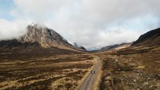 A drone shot showing 2 cyclists on the West Highland Way with Buachaille Etive Mor in the background