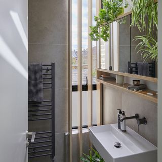 Grey bathroom with wooden slats and houseplants