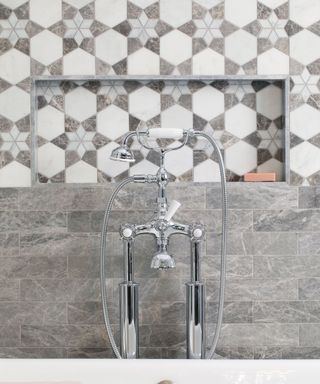 Gray bathroom tiles by Claybrook behind a silver shower head.