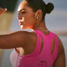 Woman wearing pink Fabletics sports bra, shielding her eyes from the sun