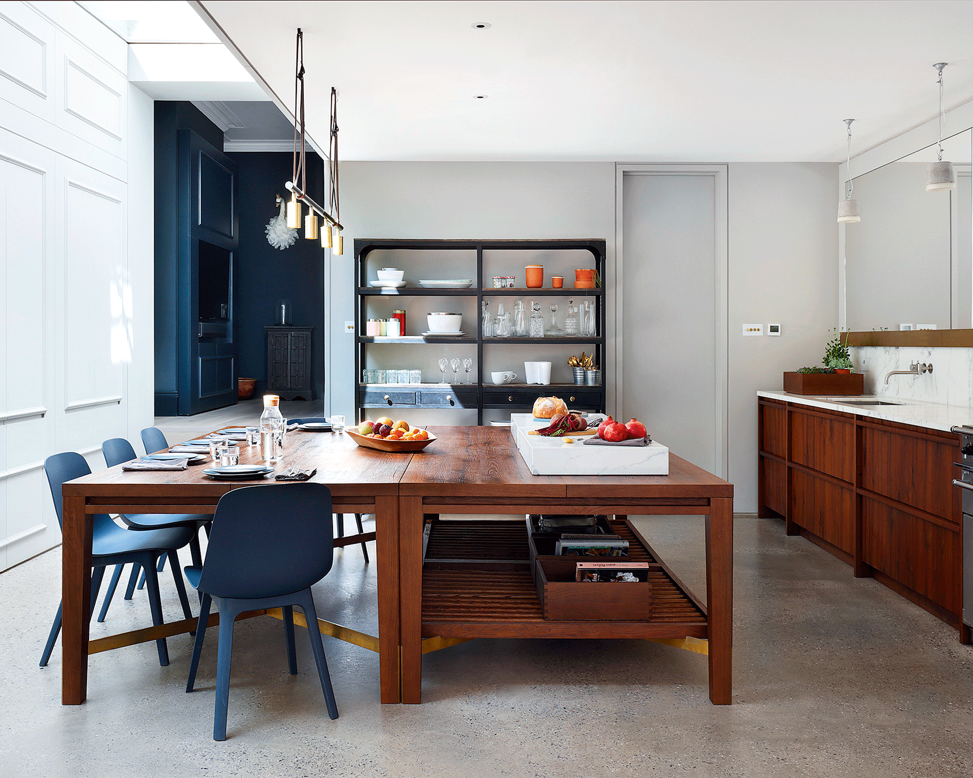 A freestanding kitchen with a large wooden island with blue chairs