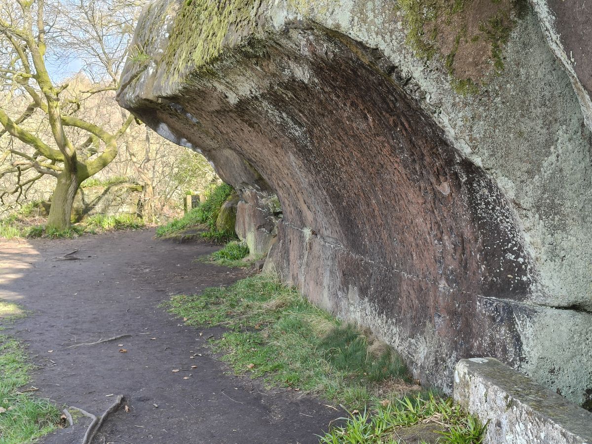 Large boulder next to a path and trees