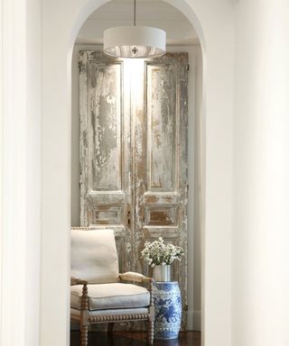 Hallway light in alcove with white chair, chinoiserie detail vase and distressed cabinet