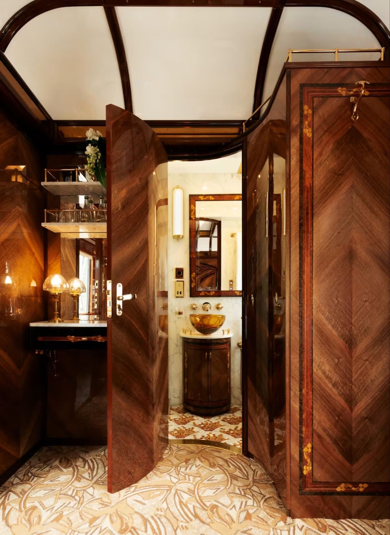 A sleekly furnished train cabin features golden and wooden decor.
