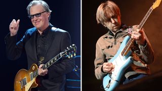 Joe Bonamassa smiles onstage and raises his hand. He holds a Gibson Les Paul Standard. Eric Johnson wears a brown shirt and plays a Daphne Blue Fender Stratocaster.