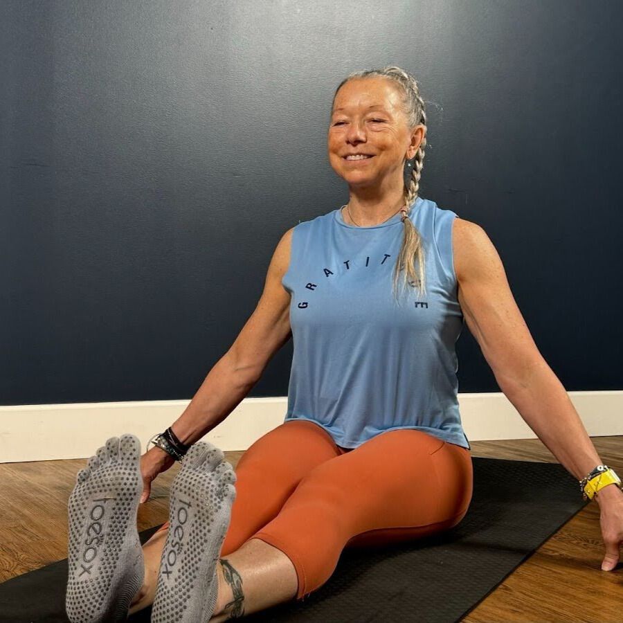 Woman sits on the floor with her legs extended in front of her demonstrating an ankle movement