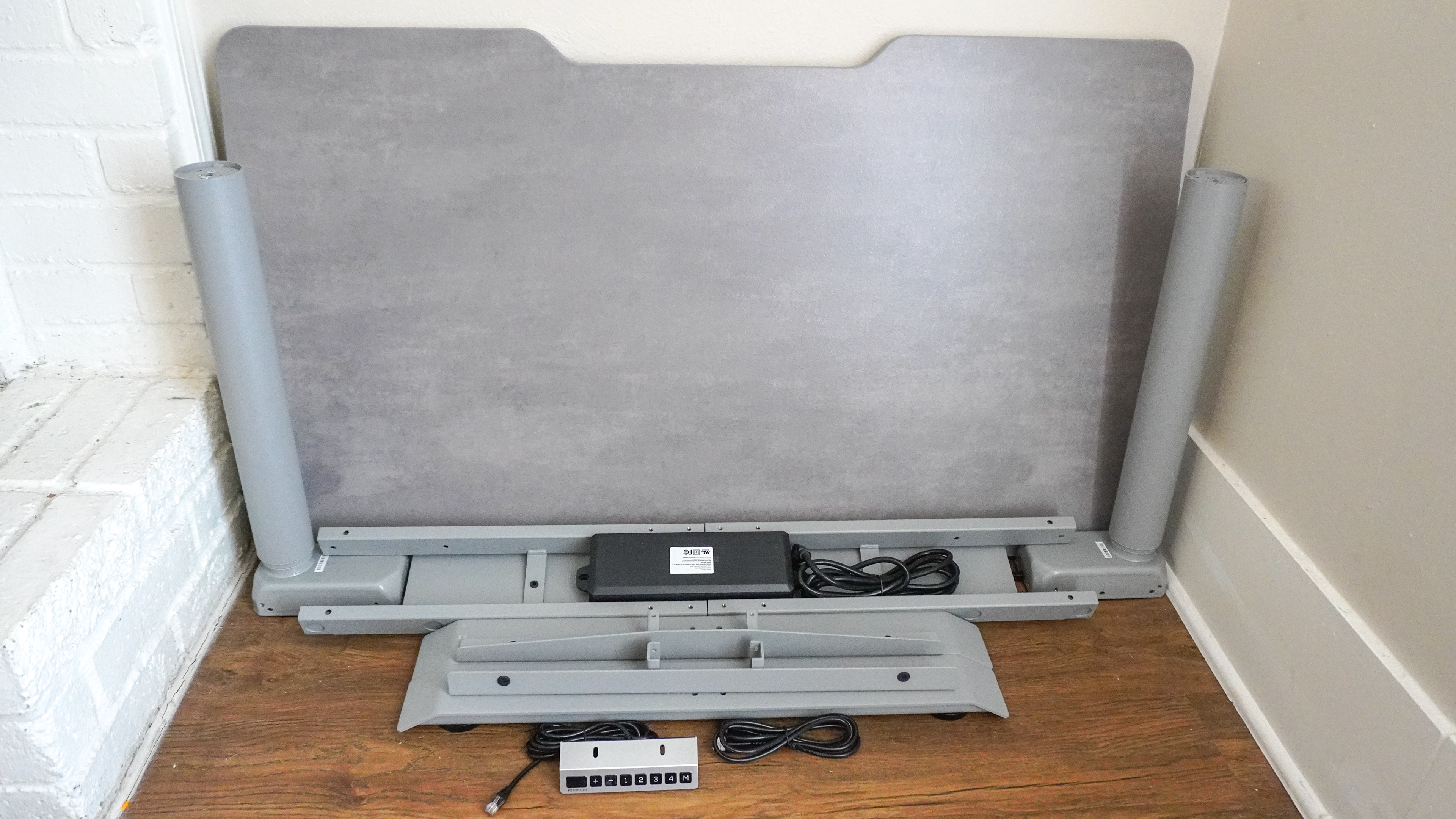 The Hinomi S1 standing desk unboxed with all of the parts laid out on the floor