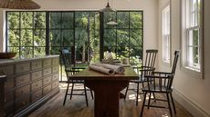 a garage DADU conversion transformed with large glass and steel doors with a view to the backyard, a large dark wooden kitchen island and a rustic farmhouse table with antique chairs