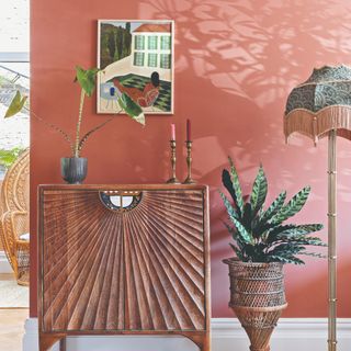 A living room with a terracotta-painted wall and a vintage-style tassel-trim floor lamp