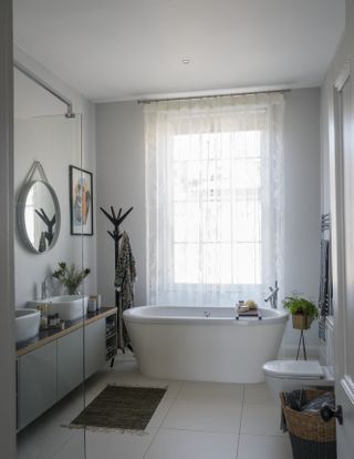 A bathroom with sheer curtains next to the bathtub