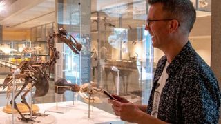 Man standing by the preserved skeleton of a Dodo at Cambridge University's Museum of Zoology.