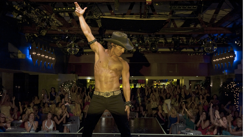 A male stripper with his shirt off wearing a cowboy hat