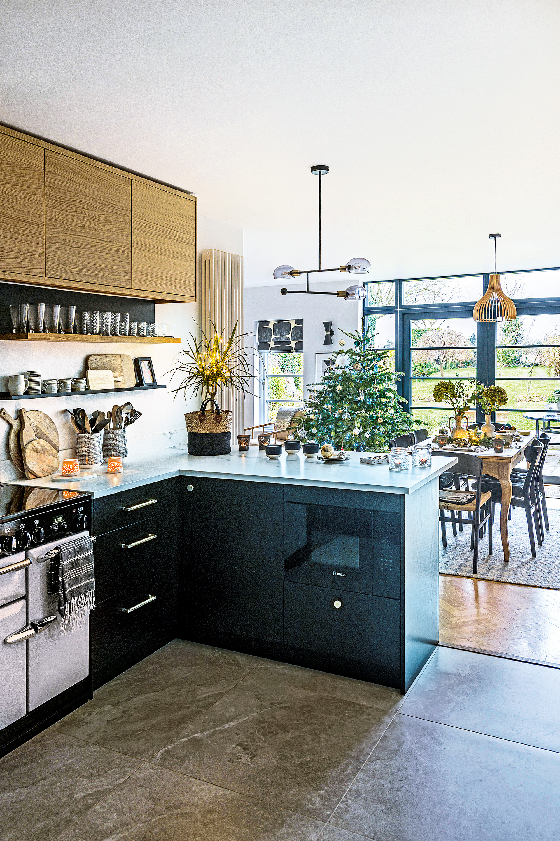 open plan kitchen with oak wall cupboards and black base units and tiled floor