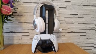 The SteelSeries Arctis Nova Pro Wireless white edition on a headset stand with a white brick background