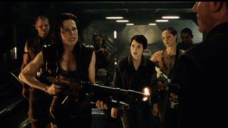 Sigourney Weaver stands with Ron Perlman and Winona Ryder holding a gun in Alien Resurrection.