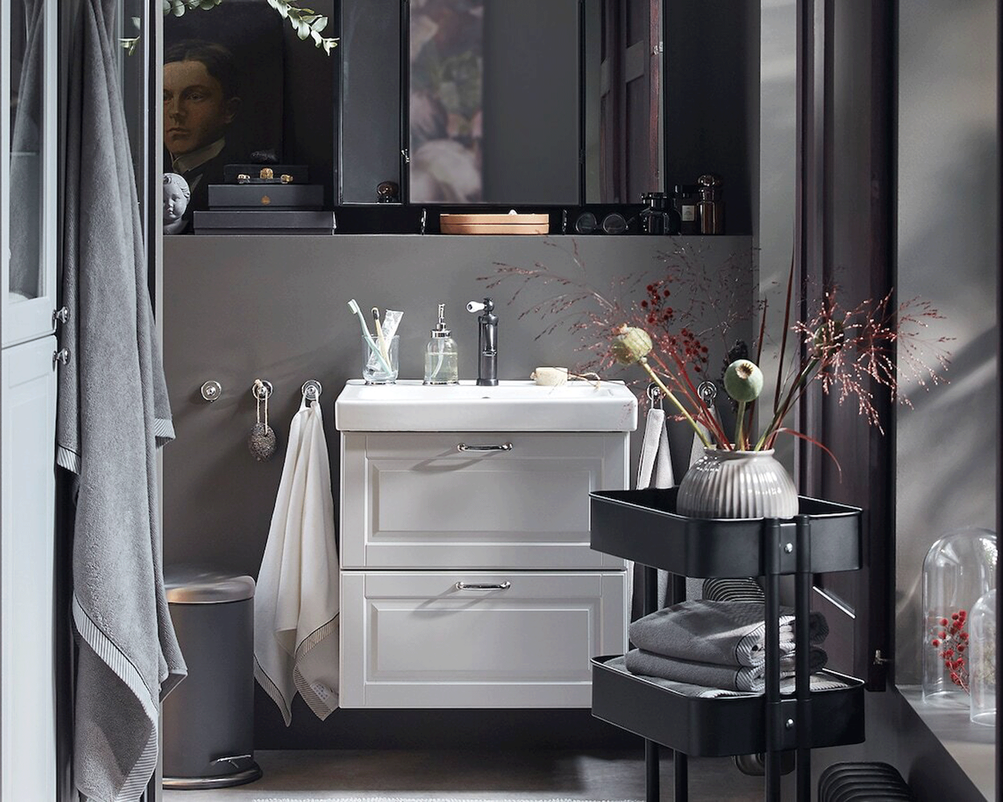 Small dark gray interior bathroom with light gray and black wash stand, with white sink and dressing table