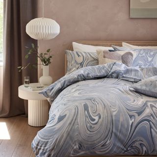 bedroom with pale pink walls and blue marbled bedding George Home