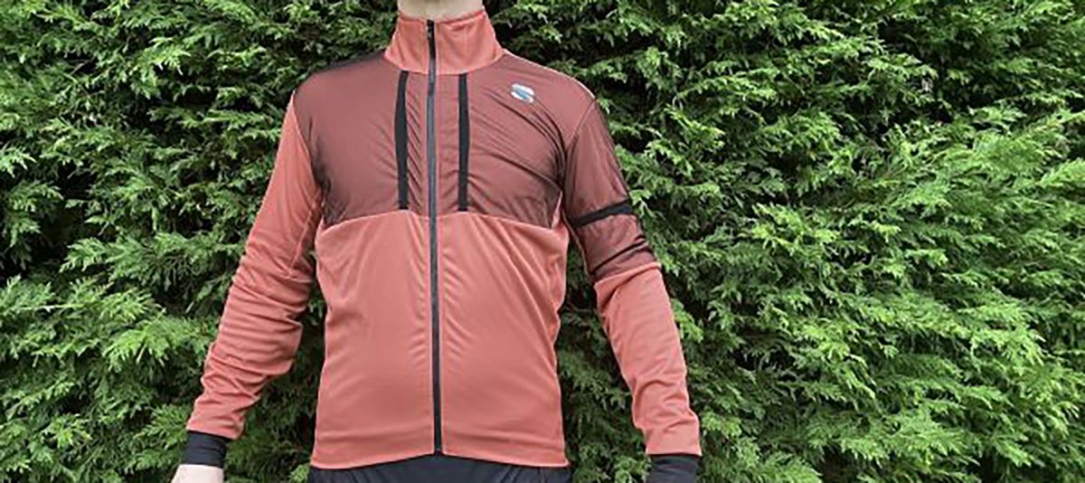 Man wearing Sportful Supergiara gravel jacket in front of hedge