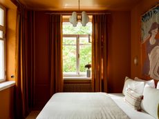 an orange color drenched bedroom with orange curtains and a tapestry on the wall