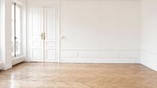 An empty apartment with white walls and a wooden floor