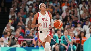 Napheesa Collier #11 of the USA Women's National Team dribbles the ball, dressed in a white vest and shorts, during the women's basketball at the 2024 Paris Olympic Games.