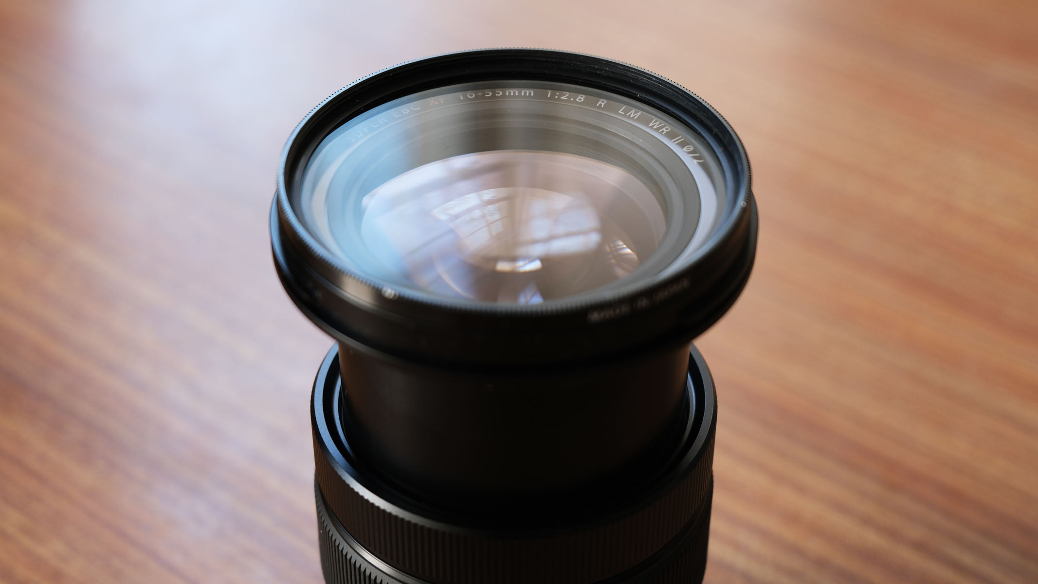 The Fujifilm XF 16-55mm f/2.8LM WR II lens upright with an extended focal length, showing the front lens element