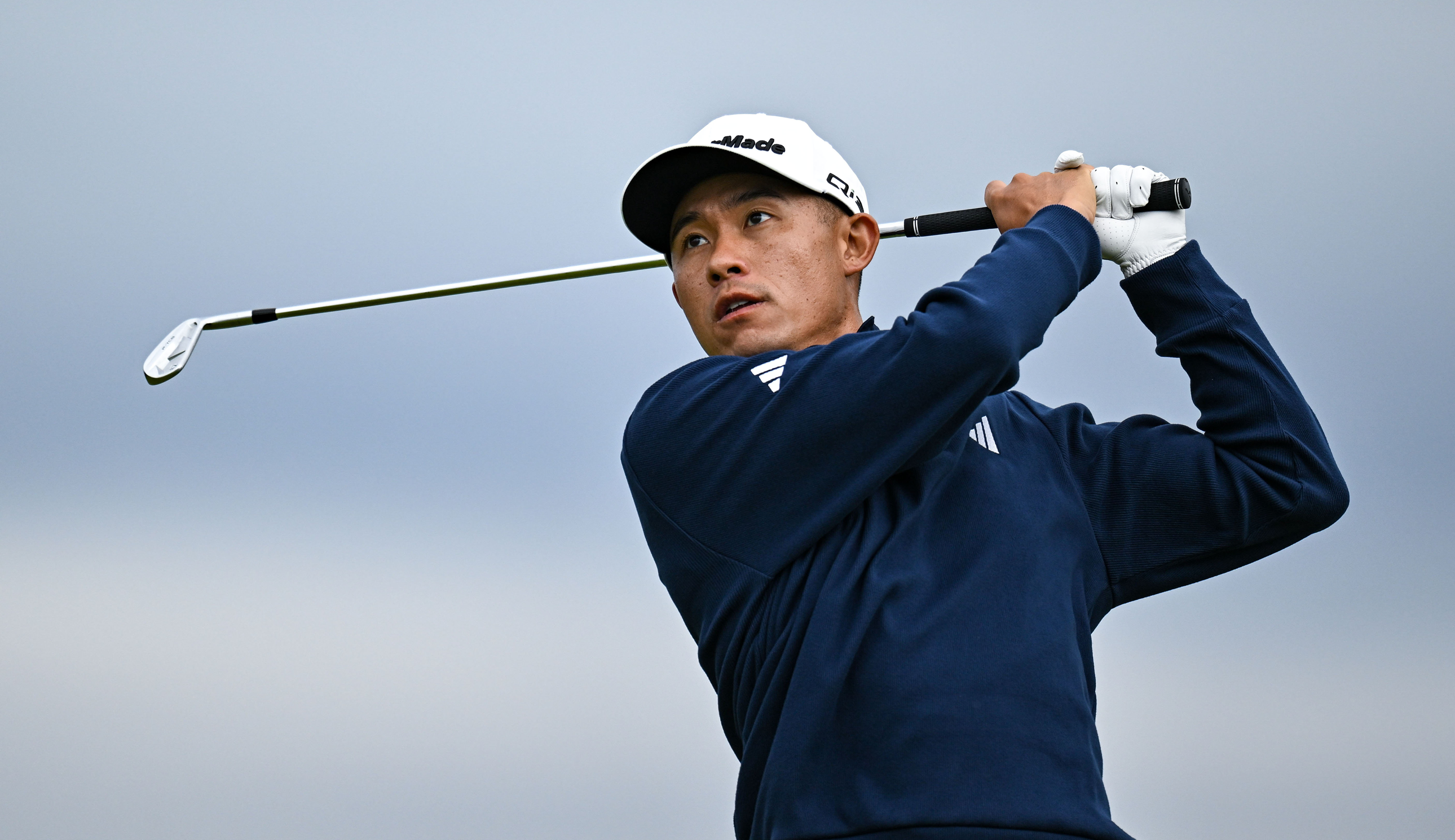 Collin Morikawa hits an iron shot and watches its flight