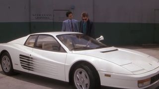 Don Johnson and Philip Michael Thomas standing behind a white Ferrari Testarossa in Miami Vice.