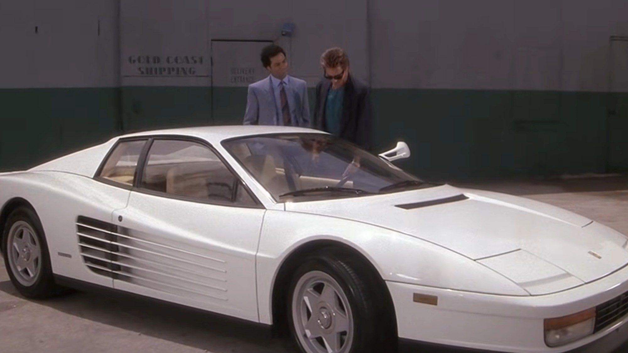 Don Johnson and Philip Michael Thomas standing behind a white Ferrari Testarossa in Miami Vice.