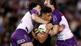 Izack Tago (C), if the Penrith Panthers, is squashed between two tackling Melbourne Storm NRL players.