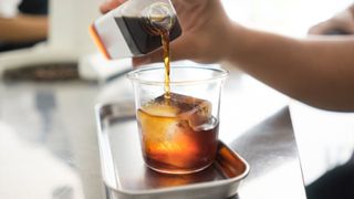 cold brew coffee being poured over ice on a tray