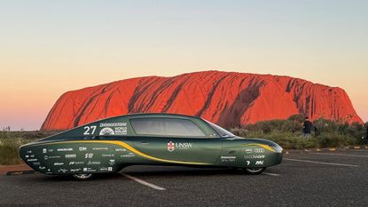 A photo of UNSW's Sunswift 7 car pictured in front of Uluru in Australia's Northern Territory.