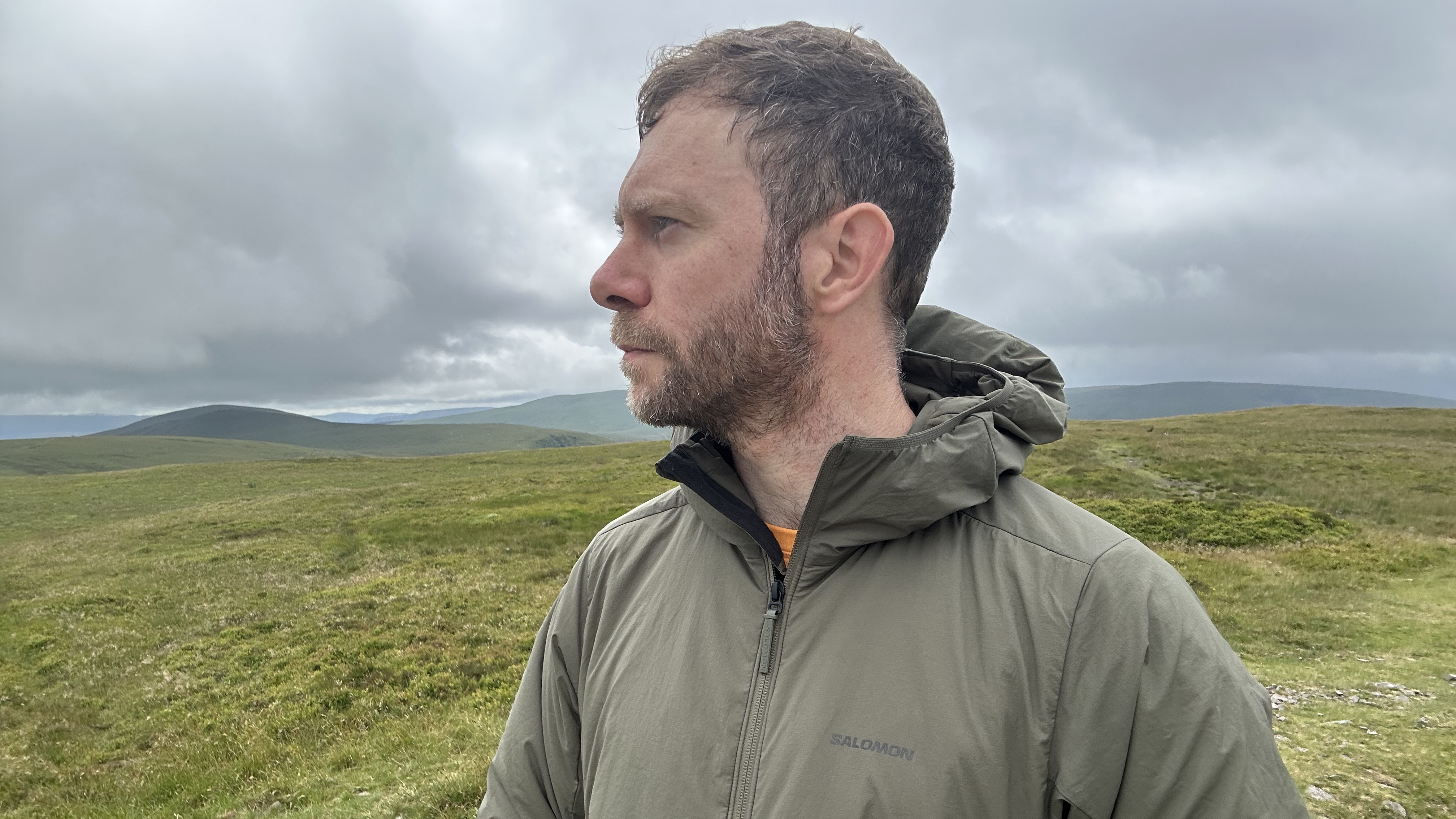 A hiker wearing the Salomon Mountain Flex Insulated Jacket in the hills