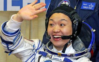 Yi So-yeon wearing her spacesuit smiles and waves.