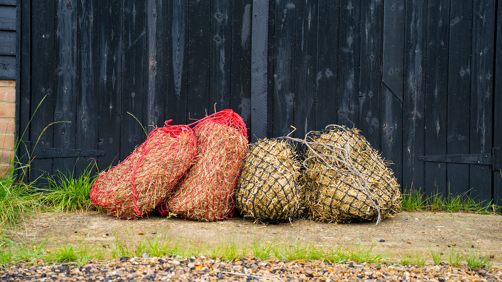 Small hole haynets containing forage left in a pile of the floor