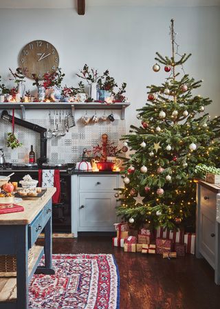 Christmas tree in unfitted farmhouse kitchen with aga and farmhouse table used as island