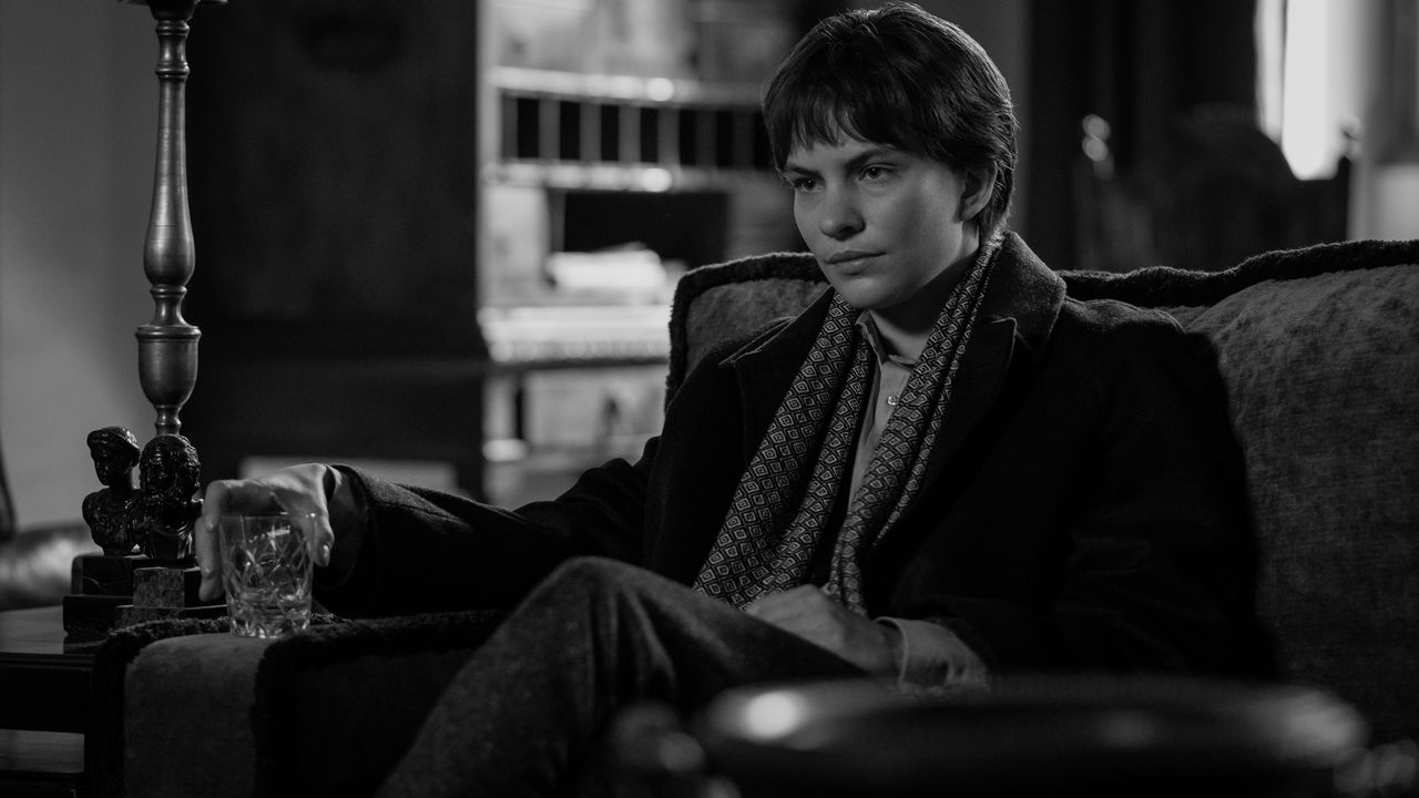 Eliot Sumner as Freddie Miles, sitting in an armchair and holding a glass, in Episode 105 of Ripley