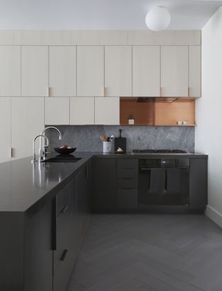 A kitchen with white upper cabinets and black lower cabinets