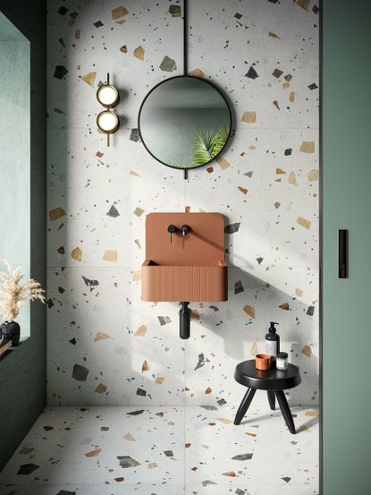 An example of tile trends 2021, showing terrazzo bathroom tiles behind a brown sink and black mirror.