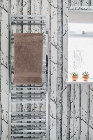 tree patterned wallpaper and a towel rail in a bathroom